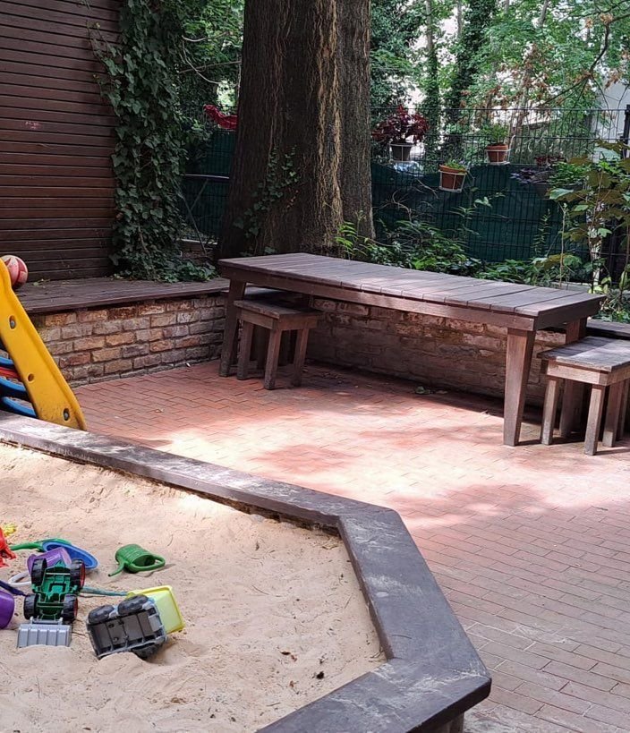 Sandkasten mit Spielzeug und gepflasterter Hof
